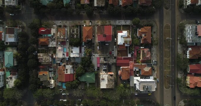 Aerial view of buildings with red roofs and lush green trees, juxtaposed against an empty road with few cars, Maputo, Maputo, Mozambique.