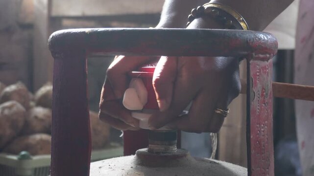 Hands disconnecting LPG regulator from gas cylinder safely