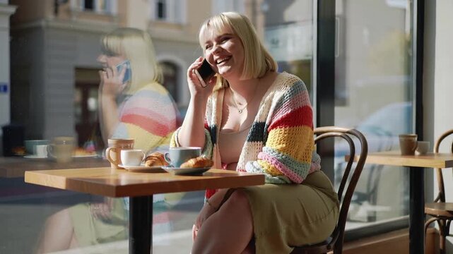 plus-sized Woman talking on the phone while sitting in cafe 