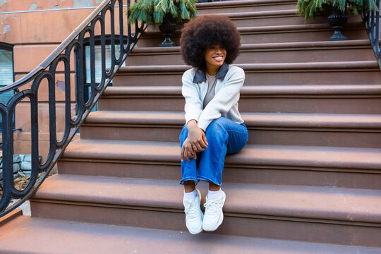 Smiling woman sitting on brownstone steps in harlem new york city