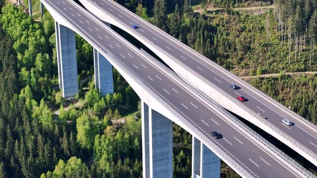Aerial view of a concrete bridge with vehicles cutting through a dense green forest, creating a stark contrast, Wolfsberg, Carinthia, Austria.