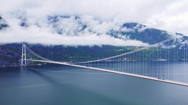 Aerial view of Hardangerbrua bridge contrasting against the dark waters and cloud-covered mountains, Bergen, Vestland, Norway.