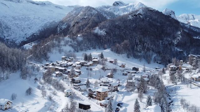 Aerial view of snow blanketed Balme, with village nestled amidst the stark white landscape and towering peaks, creating a serene winter scene, Balme, Piedmont, Italy.