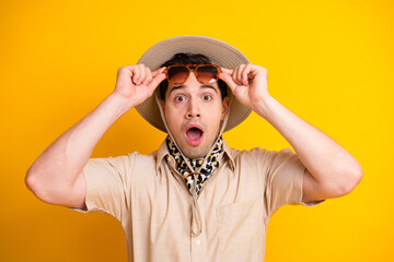 Surprised man in safari hat adjusts sunglass on bright yellow background travel fashion and adventure