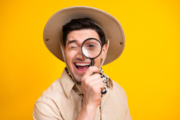 Bright yellow background adventurer with safari hat using magnifying glass to explore and smile stock photo of a curious young man