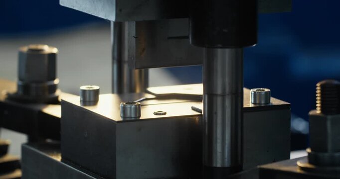 Close up of metal press mold operating inside industrial factory during continuous manufacturing process