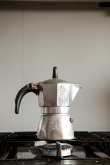 A silver coffee pot sits on a stove burner