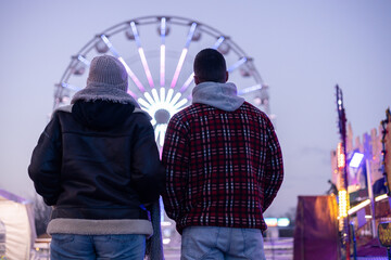 Couple watching ferris wheel lights at amusement park