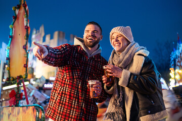 Happy couple enjoying beer at festive fairground evening