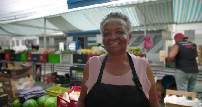 African American elderly woman portrait at outdoor produce market smiling gently and reflecting pride familiarity and human presence in everyday local street commerce