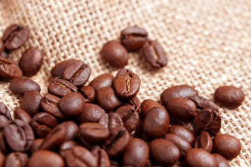 Obraz premium Close-up of freshly roasted coffee beans on rough burlap. Rustic View