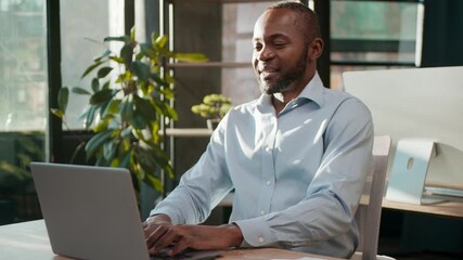 Carefree African American businessman dancing typing laptop in office listening music enjoying audio male mature business man 40s executive celebrating good work winning online dance using computer