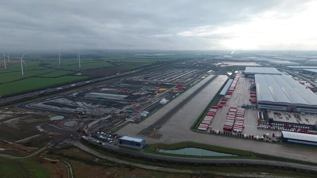 Cinematic bird's eye perspective of a major industrial transport hub in Crick England with warehouses and rail freight links for UK import and export.