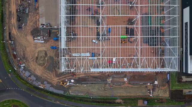 Aerial Drone Close Up of New Build Industrial Warehouse Construction Site in UK, Steel Frame Structure and Roofing of Modern Logistics Hub in England
