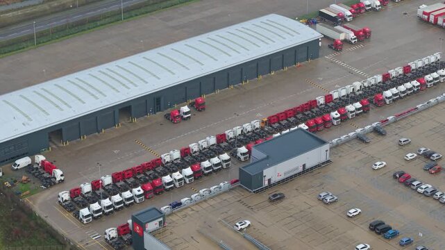 Aerial drone close up of heavy goods vehicles and trailers parked in loading bays at a major distribution centre near Crick Northamptonshire UK day.