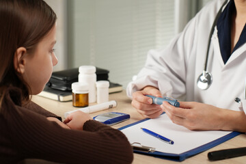 Fototapeta premium A female doctor in a white coat showing a child how to use an insulin injection pen during a clinical consultation. Concept for pediatric diabetes care and patient education