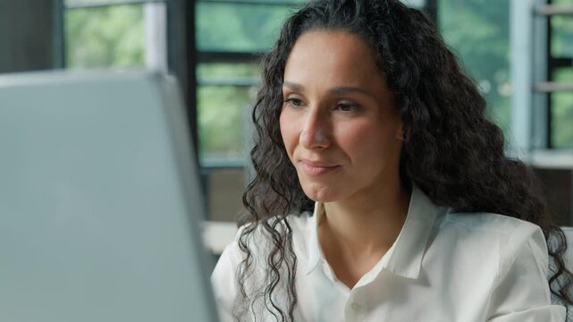 Close-up pensive Hispanic business woman in office working with computer smiling thinking businesswoman female girl think create idea inspiration worker journalist writer typing pc online internet