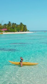 Young woman happily strolling through crystal clear waters with her surfboard in a tropical lagoon, surrounded by palm trees and sandy beaches, capturing the essence of a perfect summer vacation