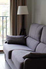 empty apartment living room, sofa with floor lamp and window with curtains in the background