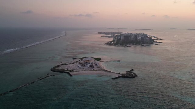 Maafushi, Maldives: Aerial orbit drone footage of small island and Maafushi in Kaafu Atoll of Maldives during a dramatic sunset in the Indian Ocean