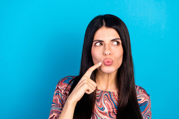 Young woman in a stylish patterned shirt poses playfully against a blue background for fashion lifestyle advertising and stock photo use