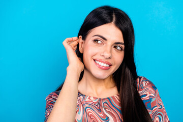 Fototapeta premium Portrait of a young woman smiling in a colorful printed top against a blue background