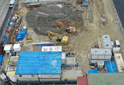 Aerial view of excavators amid a construction site's raw earth and temporary structures under a blue tarp, Halkali Merkez, Kucukcekmece, Istanbul, Turkey.
