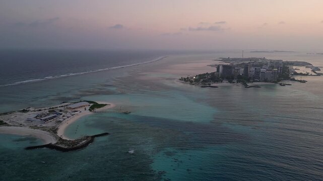 Maafushi, Maldives: Aerial drone footage of small island and Maafushi, islands in Kaafu Atoll of Maldives. Taken with backward motion with wave in the background at sunset