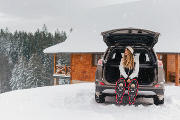 Blonde Woman in Snowshoes Sitting in Car Trunk