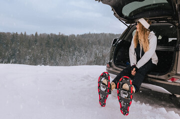 Woman Sitting in Car Trunk Equipped for Snowshoeing