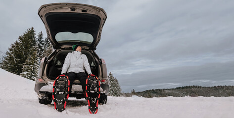 Person Sitting in Car Trunk Equipped for Snowshoeing