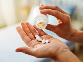 Impotence and physical weakness Person pouring white pills from bottle into open palm 1