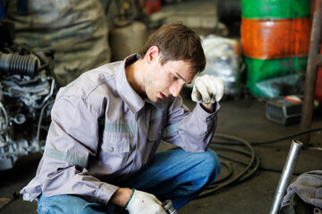 Naklejka premium Worker feeling tired from hard work in a vehicle dismantling shop