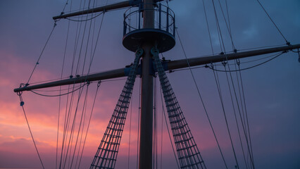 Obraz premium Sailing ship mast against colorful sunset sky, showcasing ropes and rigging in serene atmosphere