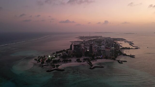 Maafushi, Maldives: Aerial orbit drone footage of dramatic sunset over Maafushi, local island in Kaafu Atoll of Maldives in the Indian ocean. 