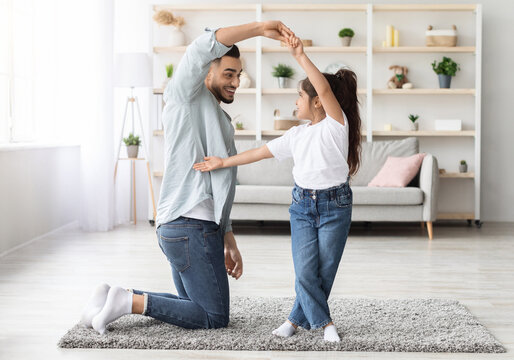 Loving arabic father dancing with his adorable little daughter at home, happy dad teaching pretty long-haired female kid dancing waltz, single father spending weekend with his child, copy space - Powered by Adobe