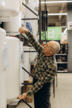 Senior man measuring water heater dimensions in store