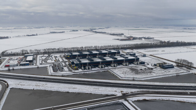 Aerial view of the vast Datacenter complex amid snow-dusted fields under a somber sky, Agriport, Noord-Holland, Netherlands.