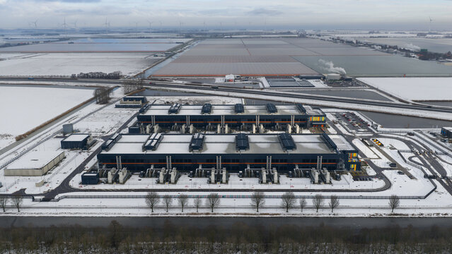 Aerial view of a vast, snow-dusted datacenter complex standing starkly against the flat, wintry landscape, Datacenter, Noord-Holland, Netherlands.