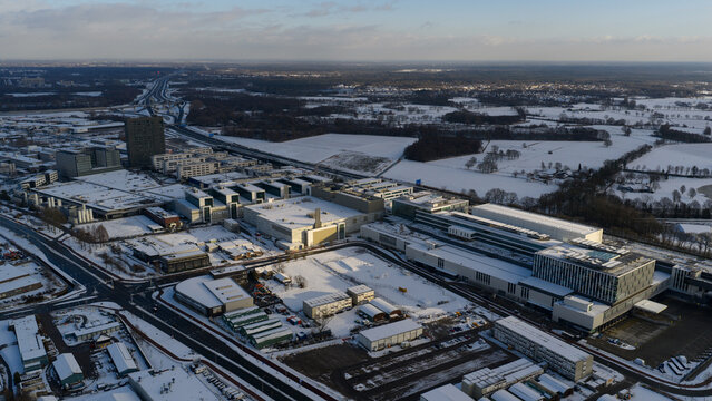 Aerial view of the sprawling ASML complex dusted with snow, contrasting sharply with the dark asphalt and surrounding icy fields, Veldhoven, Noord-Brabant, Netherlands.