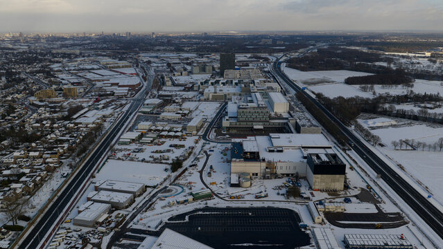 Aerial view of a snow-blanketed industrial area with stark white roofs contrasting against the muted winter sky, 6301 De Run, Veldhoven, Noord-Brabant, Netherlands.