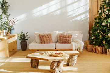 Naklejka premium Cozy living room with Christmas tree and gifts next to couch, natural wood furniture