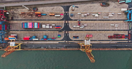 Top down rows of colorful shipping containers and gantry cranes at busy industrial port during...
