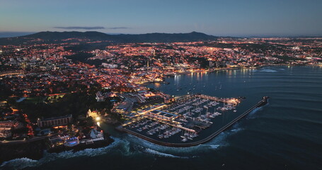 Portugal, Lisbon: Cascais glowing at dusk, aerial view of the marina and cityscape, with the Sintra mountains in the background, in Portugal. Drone