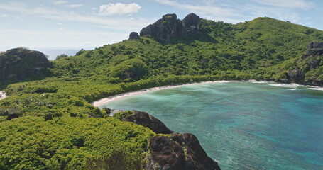 Fiji: Aerial drone view of secluded tropical bay with turquoise water, pristine sandy beach and lush green hills, perfect peaceful island paradise for travel and vacation. Aerial view drone flight