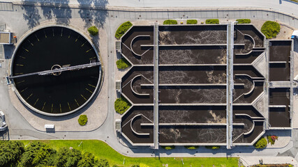 Aerial view of an advanced wastewater treatment plant with circular tanks and filtration systems integrated into a landscaped environment.