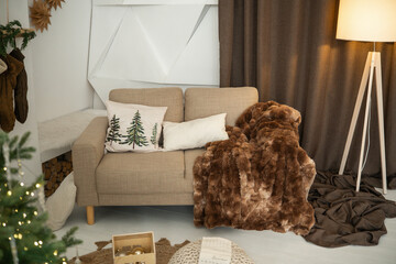 Naklejka premium Cozy living room with sofa, plush throw, festive decor, and ambient lighting.