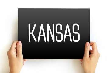 KANSAS text in bold typeface on a rectangular card held by two hands. A straightforward concept image for state name, geography, tourism, or educational content