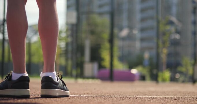 Close up of child feet on court line in sunny day. First step moment shows decision and new beginning. Future path and choice. Sports and motivation. Boy child athlete basketball player in sneakers.