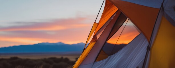 The tent glowing at sunset against distant mountains and wide open desert horizon